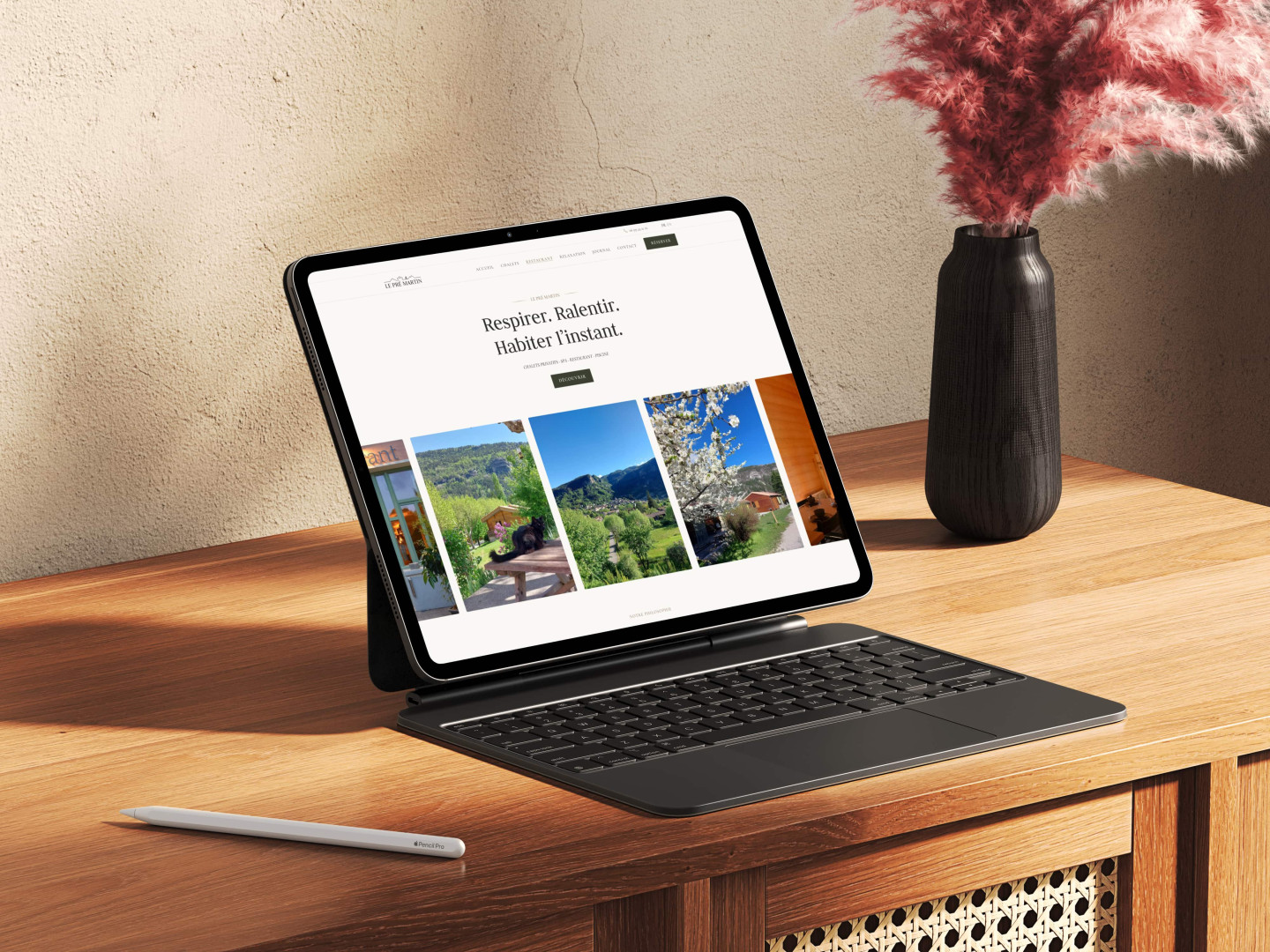 Sur une commode en bois, une tablette et un vase de fleurs, montrant le design du site du Pré Martin, conçu et développé par Humatis.